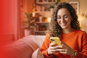 Mujer sonriente usando su celular nuevo en casa tras renovar su equipo 5G con Claro Costa Rica